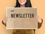 Person holding a sign saying "Newsletter"
