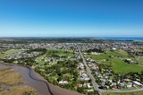 Aerial view of a residential area with an estuarine river in the foreground, arterial road in the centre and river and sea in the background 