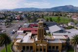 Aerial view over a town and grassed square with sandstone block Council chambers building in foreground